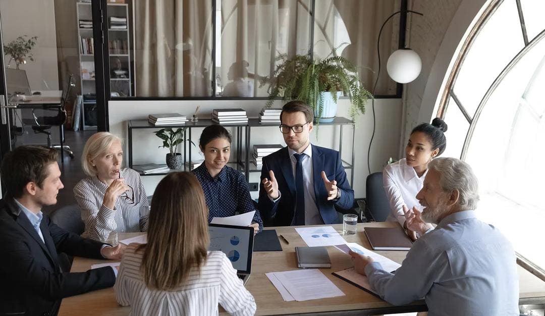 Advisers in discussion with clients around a meeting table