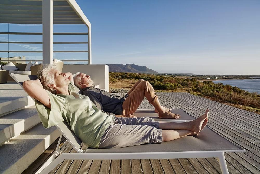 A retired couple relaxing on a terrace overlooking the sea