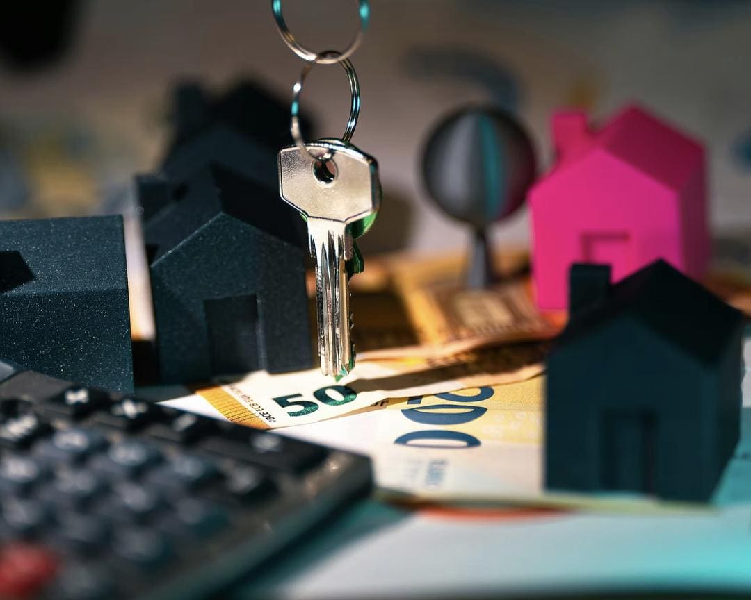 House keys, a calculator and euro notes representing savings and investment decisions